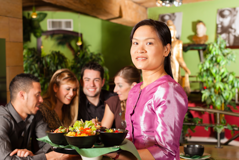 A waitress holding plates of Thai food.